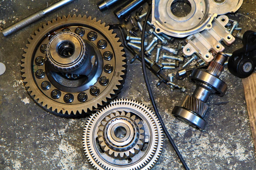 Differential ring gears, bearings and bolts laid out on a concrete shop floor